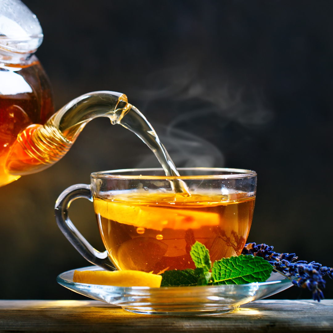 Pouring hot tea from a tea pot into a tea cup, lemon mint